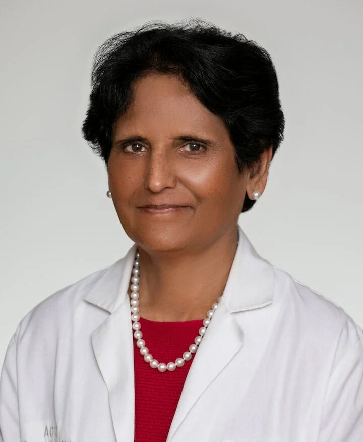 Portrait of Dr. Meera Oza wearing a white coat and pearl necklace.