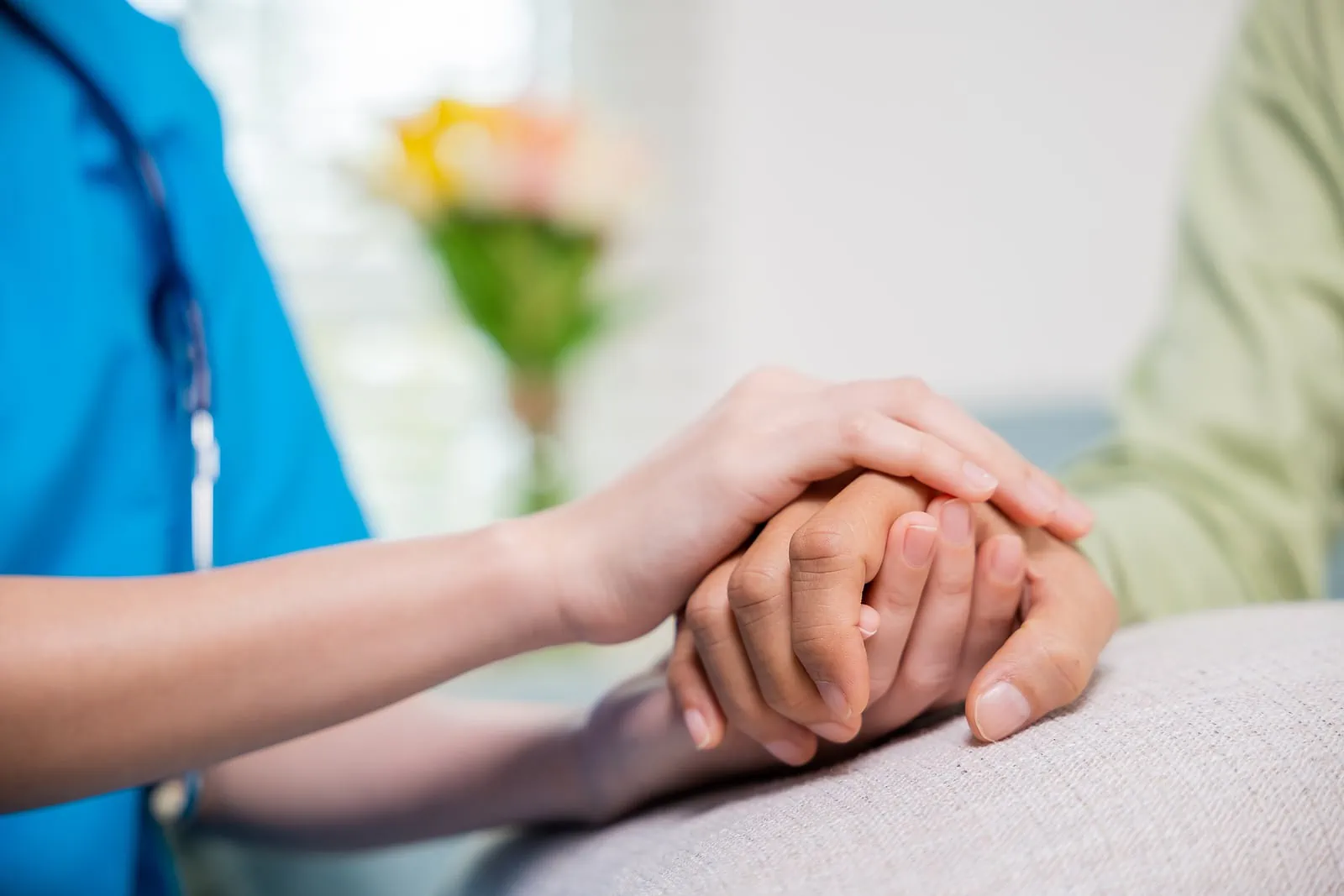 close up of doctor holding woman's hand in support