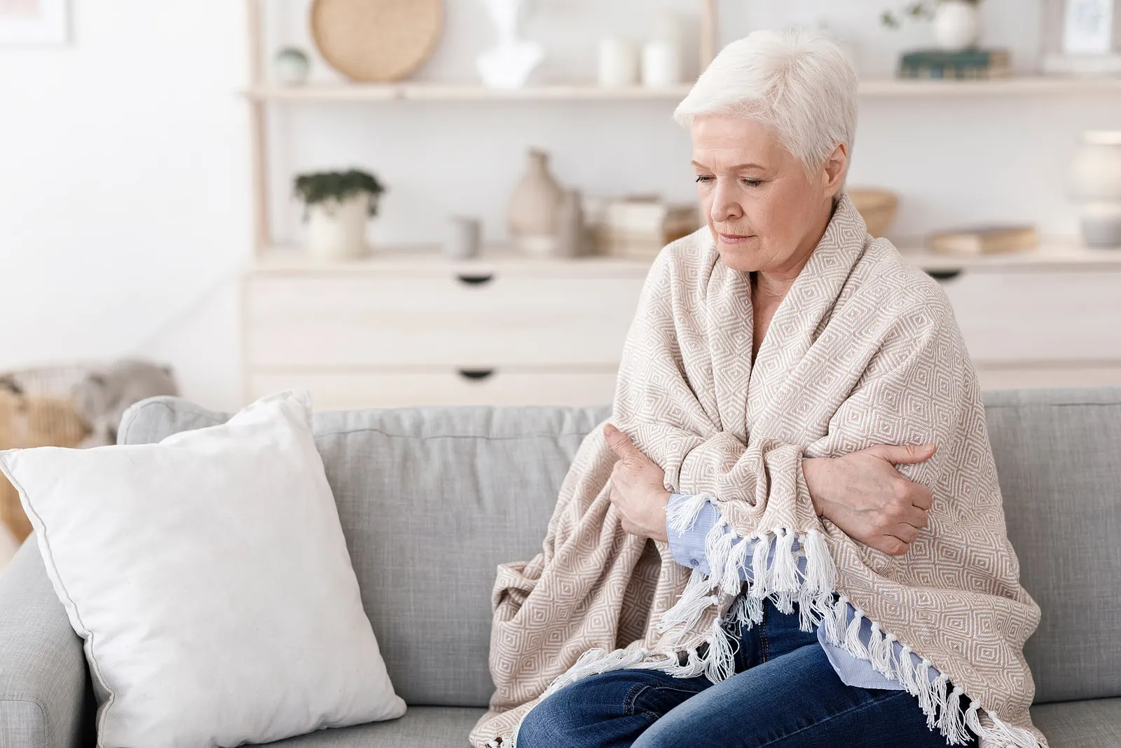 Woman sitting on couch covered with blanket