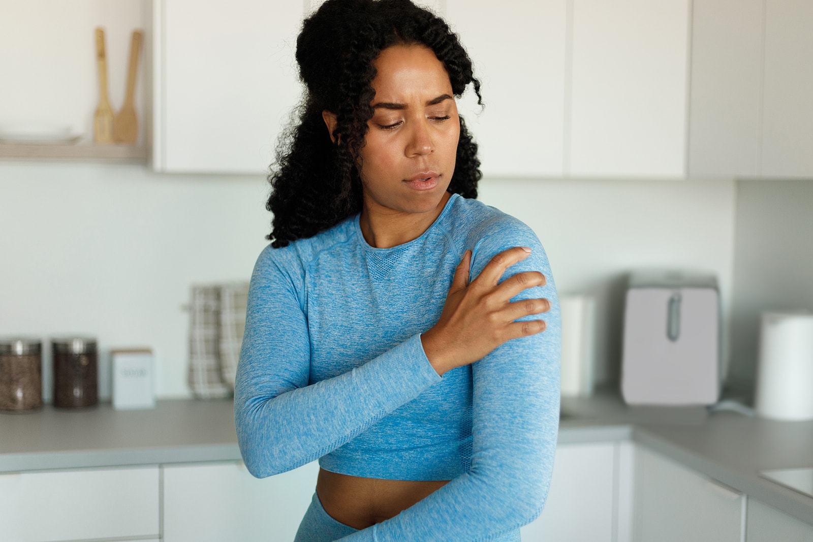 Athletic woman putting hand on shoulder, having shoulder pain