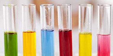 Six test tubes filled with green, yellow, blue, red, yellow, and pink liquids.